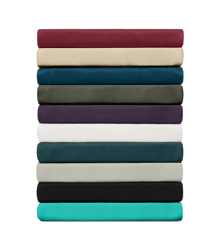 Stack of fitted bed sheets in various solid colors, neatly folded and arranged to show color variety and fabric quality.